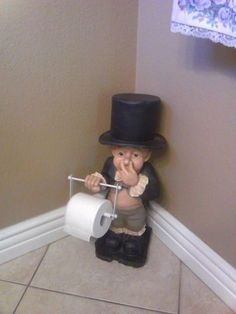 a statue of a boy with a top hat on holding a roll of toilet paper