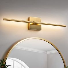 a bathroom with a mirror and lights on the wall next to a potted plant