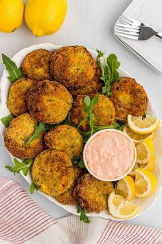 a white plate topped with crab cakes next to lemon wedges