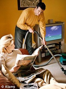 a man and woman are in the living room with a vacuum cleaner on their laps