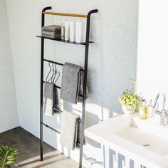 a towel rack in the bathroom with towels on it and two candles next to it