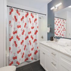 a bathroom with a shower, sink and toilet covered in red cherries on the shower curtain