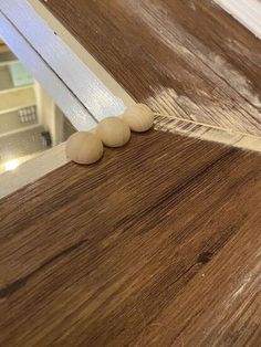 three wood beads are on the edge of a wooden counter top with a mirror in the background