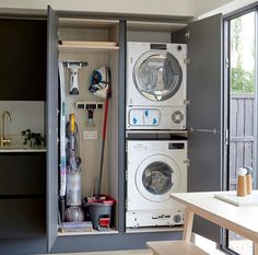 a washer and dryer are in an open cabinet next to the kitchen table