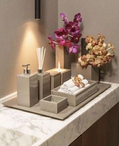 a bathroom sink with soap dispensers, candles and flowers on the counter