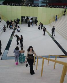 many people are walking up and down the stairs in an open area with yellow railings