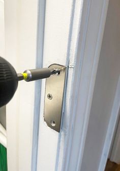 a door handle with a screwdriver attached to the side of a white door