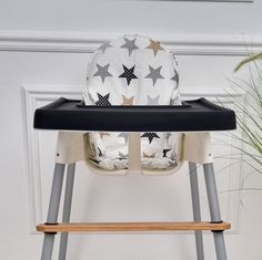 a baby highchair with a cushion on it and a potted plant next to it