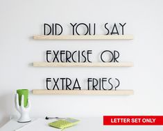 three wooden letters that say did you say exercise or extra fries? on a white wall