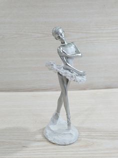 a silver figurine is standing on a wooden surface and holding a ballerina's arm