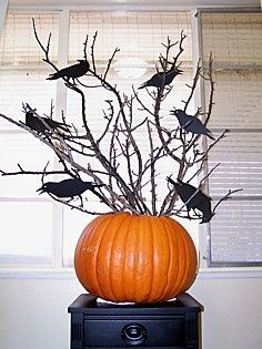 a vase filled with branches and birds sitting on top of a black table next to a window