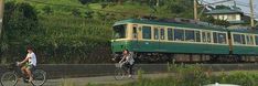 two people riding bikes next to a green train