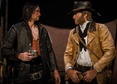 two men dressed in western clothing talking to each other with one holding a drink and the other wearing a cowboy hat