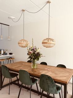 a dining room table with green chairs and flowers in a vase on the centerpiece