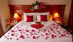 a bed with rose petals on it and two lamps