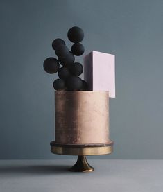 an artistically designed cake with black and pink decorations on it's top, against a gray background