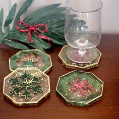 four christmas coasters sitting on top of a wooden table next to a glass vase