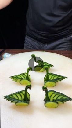 three slices of cucumber arranged in the shape of trees on a cutting board