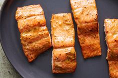 four pieces of salmon on a black plate