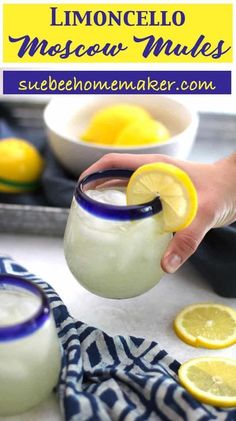 someone is holding a lemonade in a glass with ice and lemons around it