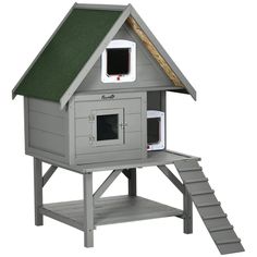 a gray birdhouse with green roof and stairs