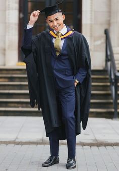 a man in a graduation gown and cap posing for the camera