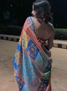 a woman in a colorful sari walking down the street with her back turned to the camera