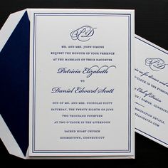 an elegant wedding card with blue and white trimmings is displayed on a black surface