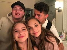 three young people posing for a photo in front of a bathroom mirror with their arms around each other