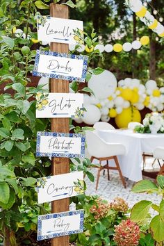 a table with white and blue decorations is set up in the middle of a garden