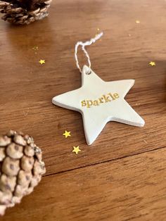 a white ceramic star ornament with the word sparkle written in gold on it