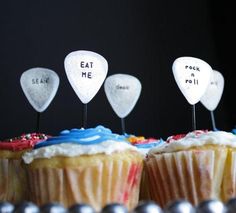 some cupcakes with white frosting and spoons on top are lined up