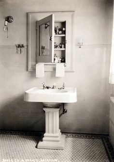 a bathroom with a pedestal sink, mirror and tiled flooring in black and white