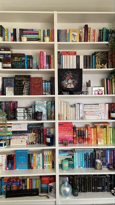 a bookshelf filled with lots of different types of books on top of white shelves