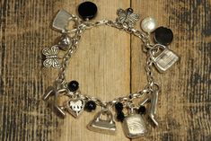 "Sterling Silver Fashion Themed Charm Bracelet. * HALLMARKS 925 and makers initials AJ * MEASUREMENTS 7 1/4\" long. Total weight is 43.8 Grams. * MATERIALS Sterling Silver, Black Onyx and Mother of Pearl. Fine sterling silver fashion themed charm bracelet featuring sterling 3d charms that include shoes, purses, compact that opens, butterflies, heart and orb. There are also a Mother of Pearl bead along with Black Onyx beads. Bracelet will arrive gift boxed. Thank you for stopping by!!" Unique Silver Bracelets With Charms, Elegant Antique Silver Charm Jewelry, Elegant Antique Silver Jewelry With Charms, Elegant Handmade Silver Charm Bracelet, Elegant Engraved Metal Charm Bracelet, Elegant Metal Charm Bracelet With Engraving, Silver Charm Bracelet For Formal Occasions, Vintage Silver Bangle Charm Bracelet, Elegant Silver Bracelets With Charms