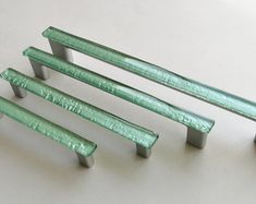 four green metal benches sitting on top of a white table next to eachother