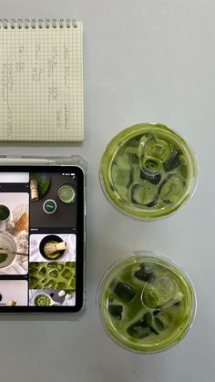 two glasses filled with green liquid next to a notebook