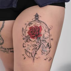 a woman's thigh with a rose in a glass ball tattoo on it,