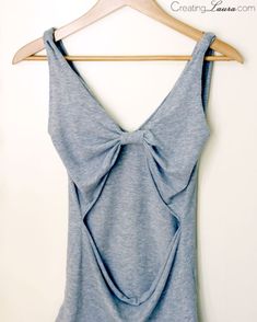 a blue tank top with a bow on the front and back, hanging on a wooden hanger