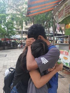 two people hugging each other in front of a food stand with an umbrella over them