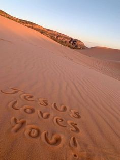 the word jesus loves you written in the sand at sunrise or sunset on top of a dune