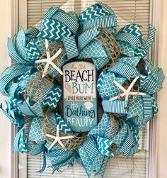 a blue and white wreath with starfishs on the front, saying beach bum