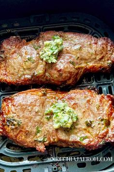 two pieces of meat with broccoli on top of it in an air fryer