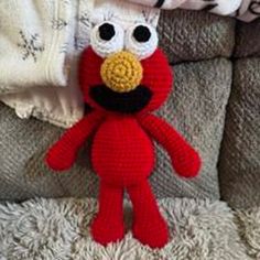 a crocheted red stuffed animal sitting on top of a couch