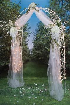 a white wedding arch decorated with flowers and tulle