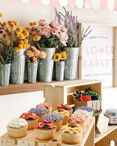 cupcakes and flowers are on display in buckets