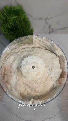 a glass bowl filled with food next to a green plant on top of a table