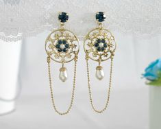 "This royalty-style gold and blue chandelier earring, which I've named Nancy, will softly touch you with a feeling of magic. Nancy is made from 24K gold plated brass and has delicate and feminine lacey filigree, set with blue crystals and Swarovski crystal pearls. A delicate Crystal Pearl teardrop swings romantically from the bottom of the pendant. Measurements: Earring length: 2.95\" (7.5cm) Pendant diameter: 0.7\" (2cm) About my work: All the jewelry in my shop is designed by me to evoke the r Bridal Chandelier Earrings, Black Gold Earrings, Chandelier Earrings Gold, Blue Bridal Earrings, Victorian Style Earrings, Black Gold Necklace, Blue Chandelier, Bridal Earrings Chandelier, Gold Chandelier Earrings