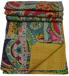 a multicolored paisley print blanket folded on top of each other with a yellow patch