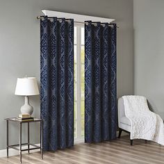 a living room with blue curtains and a white chair in front of a window on a hard wood floor